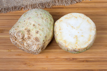 Whole and half of celery roots on a wooden surface