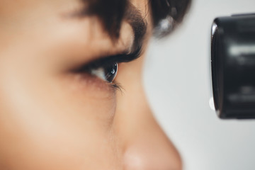 Ophthalmologist doctor woman looking at eyepiece. Ophthalmology. Close-up, horizontally.