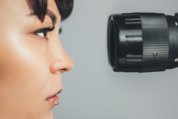Ophthalmologist doctor woman looking at eyepiece. Ophthalmology. Close-up, horizontally.