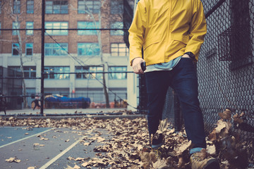 Man in yellow coat walking on the city street with fallen leaves