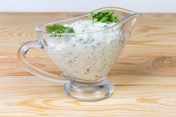 Mayonnaise sauce with herbs in glass gravy boat