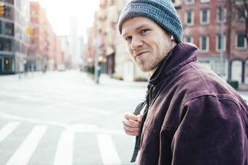 Portrait of young man crossing street on the crossroad in the city