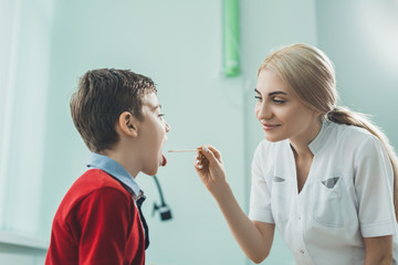 Children's ENT doctor examines boy's throat. Prevention of children's diseases.