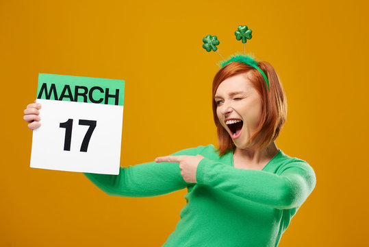 Playful Woman Pointing At Saint Patrick's Day Calendar