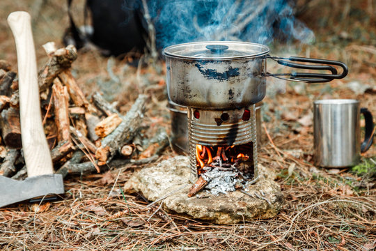 Axe Near A Firewoods, Camping Diy Woodstove, Camping Utensils And Backpack On The Background