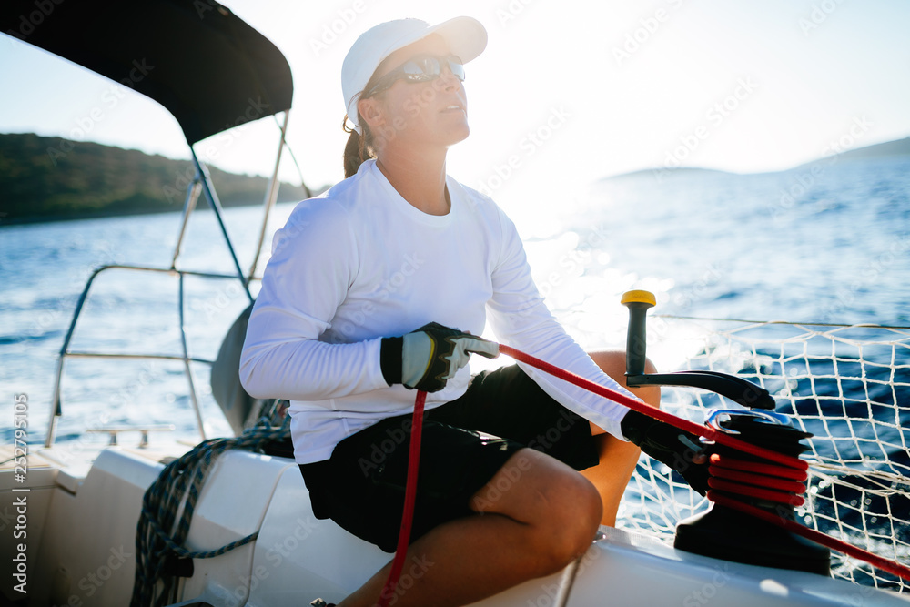 Wall mural Attractive strong woman sailing with her boat