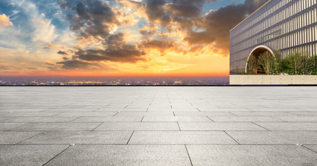 Empty square floor and modern city skyline with buildings at sunset