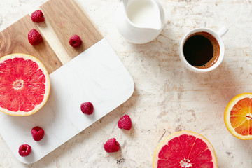 Breakfast table with fresh coffee, grapefruit, oranges and raspberries.