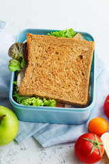 Healthy sandwich with greens, ham, tomatoes and cheese packed in plastic container. Takeaway food for lunch at school or at work.
