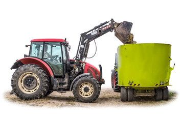 A tractor with a front loader loads silage feed into an animal feed distributor. Isolated photo. Necessary equipment for a dairy farm.