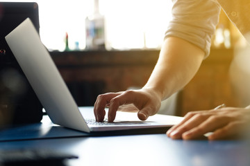 Male hands working on a computer, on a blue table, against the backdrop of a modern office with sunlight