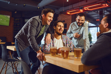 Friends talk, drink beer in a bar.
