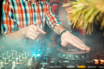 Dj mixes the track in nightclub at party