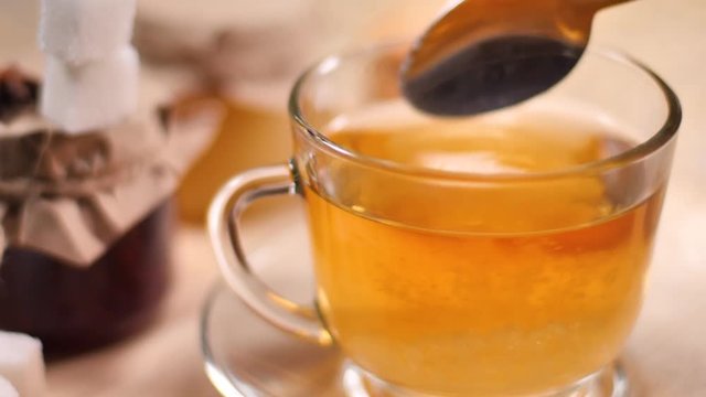 Add spoonful of sugar to green herbal tea in Cup and mix on background of honey