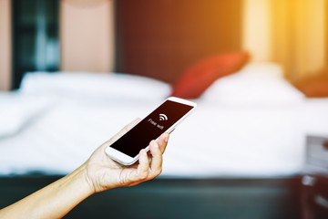 woman's hand hold mobile phone  and blurred bedroom in hotel, soft focus and vintage filter