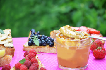 different delicious toasts on green or pink crimson background. Healthy sandwich for breakfast or snack. Toast with raspberries, strawberries, banana and blueberries and peanut butter. picnic concept