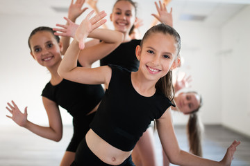 Gruppe junger fitter Tänzer, die während der Klassenschule üben