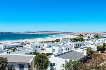 Scenic view of the picturesque town Paternoster with white houses and the turquoise ocean shoreline.