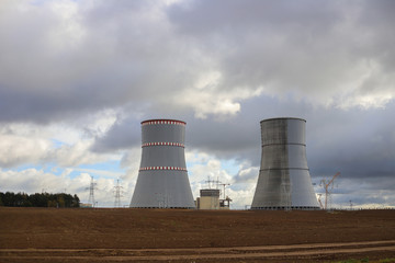 Fototapeta premium nuclear power plant on the background of a plowed field and overcast sky, average plan