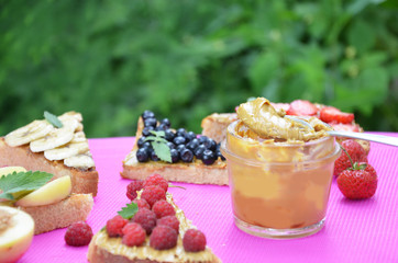 different delicious toasts on green or pink crimson background. Healthy sandwich for breakfast or snack. Toast with raspberries, strawberries, banana and blueberries and peanut butter. picnic concept