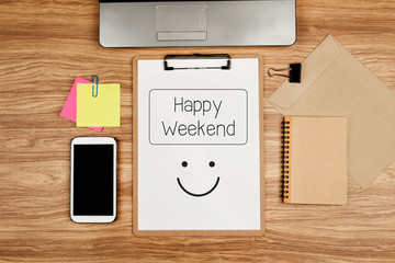 Happy Weekend text on white sheet and office supplies on wooden table