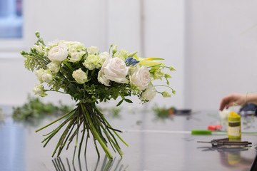 Beautiful bouquet of white flowers stands on the stems on a glossy gray table during the flower masterclass. Wedding decoration design concept