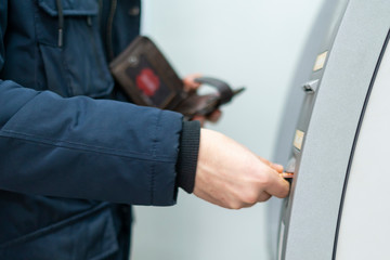 persons hand insert card in cash dispenser b
