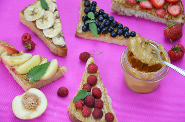 different delicious toasts on green or pink crimson background. Healthy sandwich for breakfast or snack. Toast with raspberries, strawberries, banana and blueberries and peanut butter. picnic concept