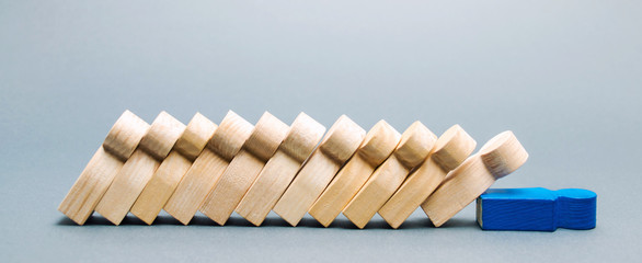 Wooden figures of people. Domino business concept. The leader does not stop the fall of employees....
