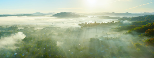 Panoramic view of the rural village and rainforest in the early morning in the rays of the sun and fog near the coast of Ngapali, Myanmar.
