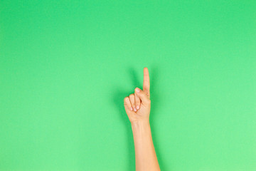 Kid hand showing one finger on green background