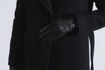 Woman in black coat and leather gloves. Closeup on white background.