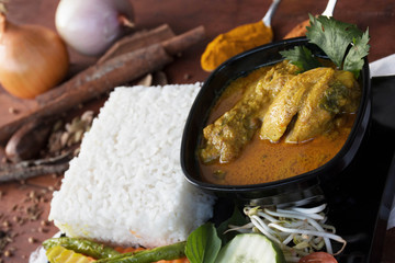 close up of a chicken curry with vegetable, herb and spices on a wooden table and white napkin