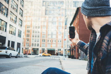 Casual man taking photo on the city street using mobile phone camera
