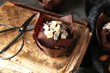Tasty almond muffin with old book on table