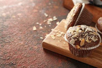 Board with tasty almond muffins on color table