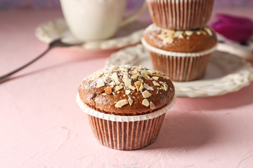 Tasty almond muffin on color table