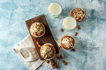 Tasty almond muffins with milk on color table