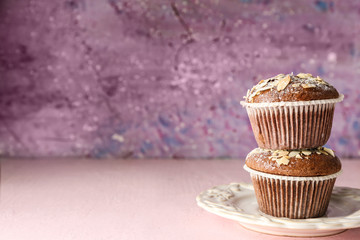 Plate with tasty almond muffins on color table