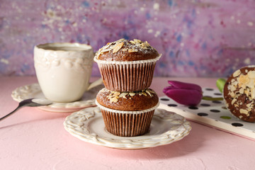 Plate with tasty almond muffins on color table