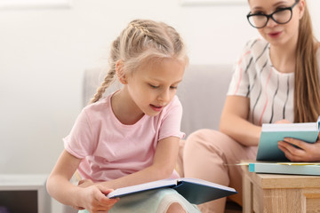 Fototapeta na wymiar Little girl reading book at speech therapist office
