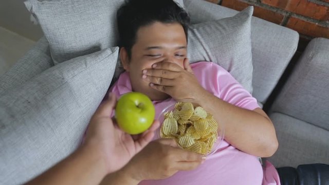 Picture of greedy person  eat snack and refusing fresh apple or healthy food
