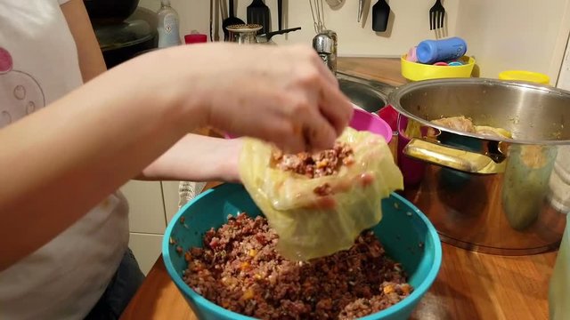 Woman preparing stuffed cabbage rolls with rice and minced meat at home kitchen in slow motion. Very delicious traditional Serbian winter season dish.