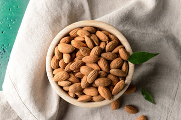 Bowl with tasty almonds on table