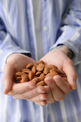 Woman holding heap of tasty almonds, closeup