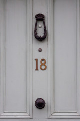 House number eighteen on an off-white door with door knocker