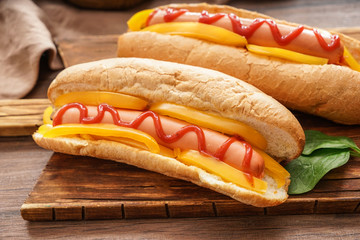 Tasty hot dogs on wooden board