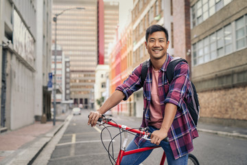 Smiling man standing with his bicycle on a city street