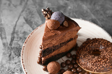 Plate with piece of tasty chocolate cake and sweets on table