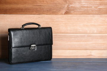 Male briefcase on table against wooden background